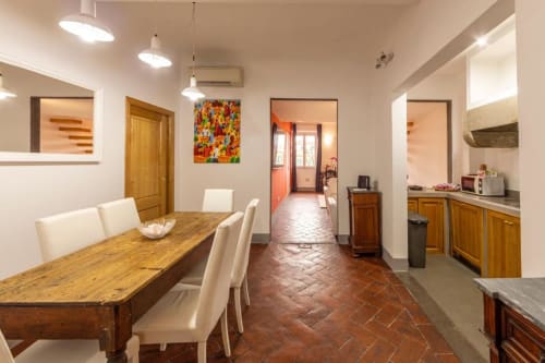 Ampia zona pranzo e cucina nell'Appartamento Fiorentino con tavolo in legno, sedie color crema, pavimenti in cotto e design moderno
