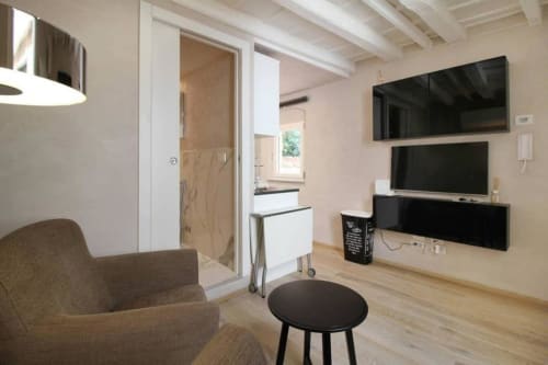 Moderna sala living con TV a schermo piatto, comoda poltrona e accesso alla cucina presso My Florentine Apartment