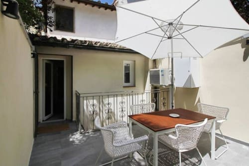 Terrazza giardino con tavolo da pranzo, ombrellone bianco e sedute moderne presso My Florentine Apartment a Firenze