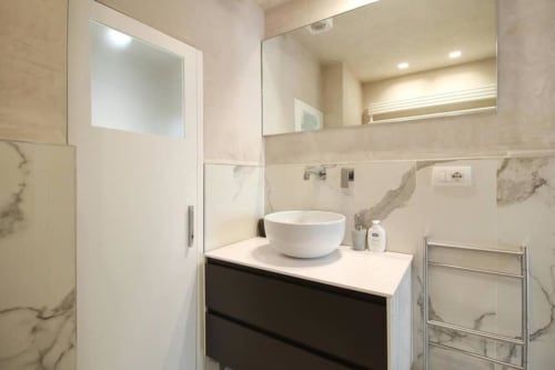 Bagno moderno con lavabo rotondo bianco, piastrelle stile marmo e specchio grande presso My Florentine Apartment, Firenze