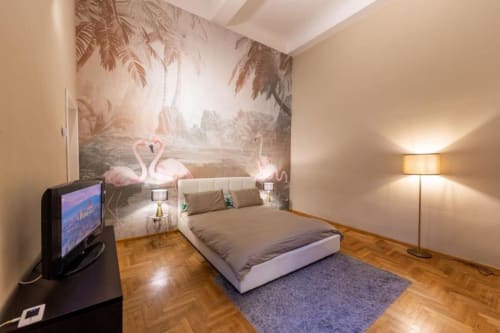 Camera da letto moderno fiorentino con murale fenicottero, letto bianco, pavimenti in legno e TV a schermo piatto