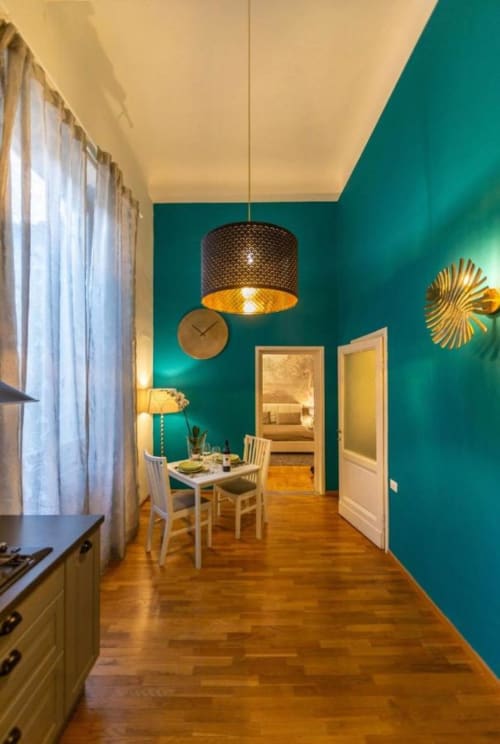 Moderna zona cucina-soggiorno con pareti turchesi, pavimenti in legno e illuminazione a sospensione nel mio appartamento fiorentino a Firenze