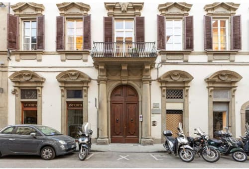 Facciata storica di palazzo fiorentino con persiane, porta in legno e motorini parcheggiati a Firenze.