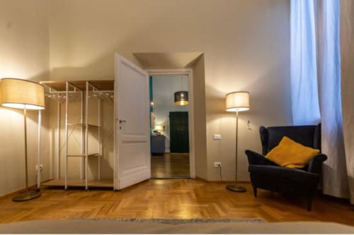 Elegante ingresso di appartamento fiorentino con parquet a spina di pesce, illuminazione moderna, poltrona nera e spazi aperti