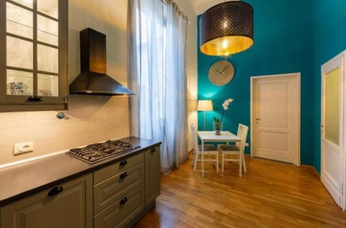Cucina moderna di appartamento a Firenze con parete azzurra, fornello a gas e zona pranzo con luce naturale