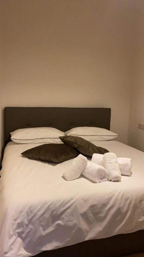 Camera da letto moderna di My Florentine Apartment a Firenze con biancheria bianca, testata scura e asciugamani arrotolati
