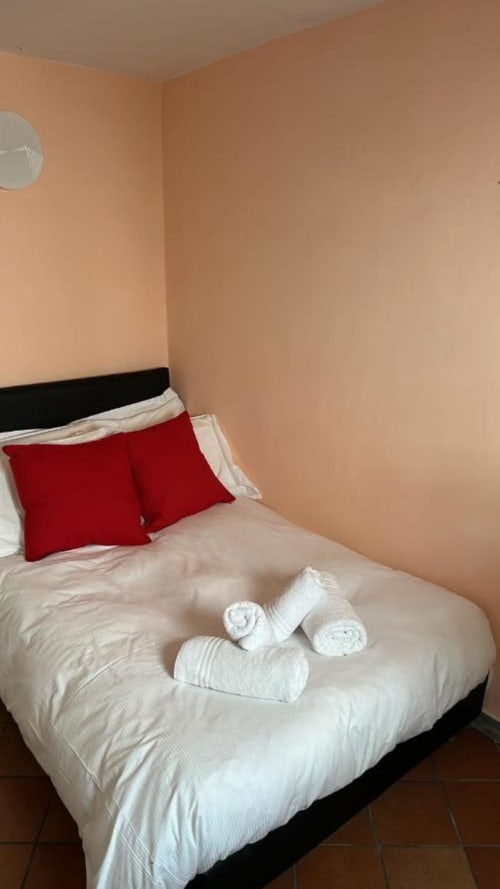 Camera da letto accogliente di My Florentine Apartment a Firenze con biancheria bianca, cuscini rossi e asciugamani arrotolati