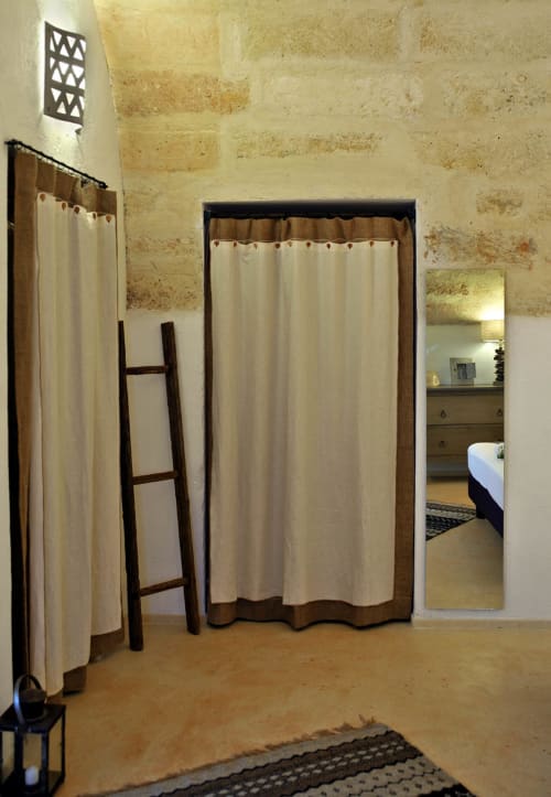 Camera da letto rustica con tende color crema, scala in legno e muri in pietra presso Masseria Picca Picca BnB