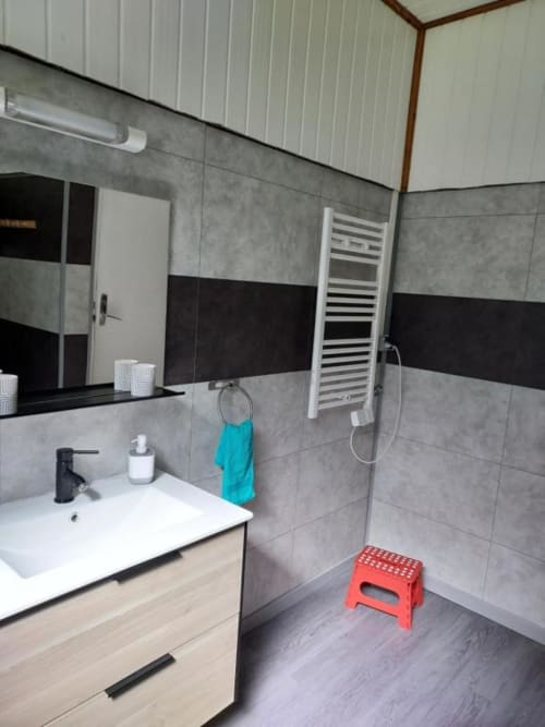 Salle de bains moderne de la villa Au pied des Sources à Cilaos avec carrelage gris, lavabo blanc et douche