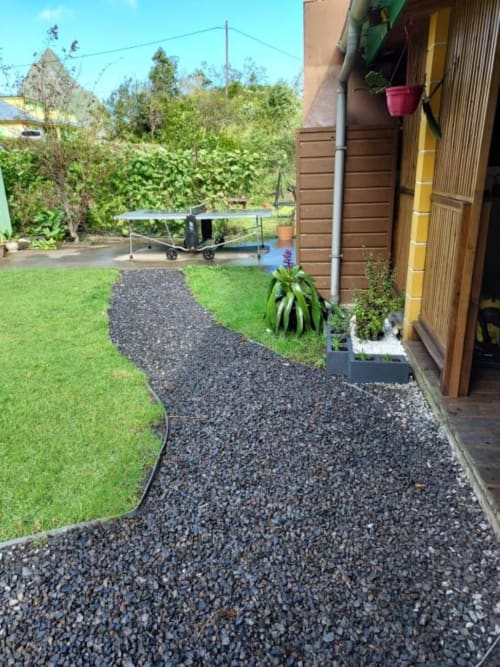 Allée du jardin de la villa à Au pied des Sources, Cilaos avec chemin en gravier, pelouse entretenue et végétation luxuriante