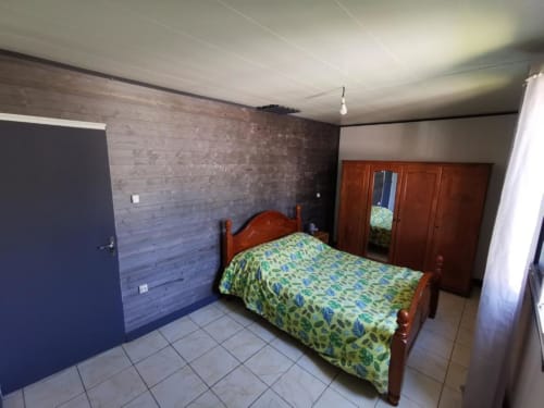 Chambre de la villa Au pied des Sources à Cilaos avec lit en bois, carrelage et vue sur le jardin