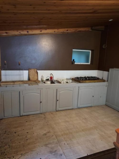 Cuisine rustique à Au pied des Sources à Cilaos : meubles blancs, plan de travail en bois et cuisinière à gaz