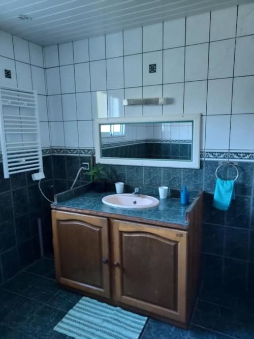 Salle de bain moderne avec carrelage turquoise, meuble vasque en bois et miroir à la villa Au pied des Sources à Cilaos
