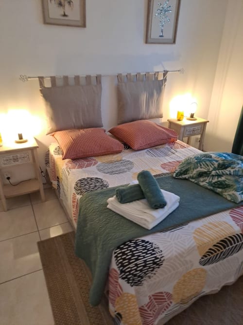 Chambre cosy de l'appartement Kay Betty avec deux lits, linge de lit aux motifs colorés, lampes de chevet et vue sur le jardin