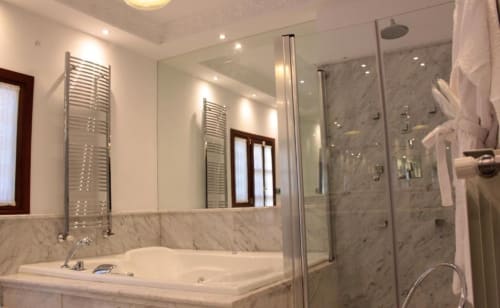 Baño de lujo en Suite Comares Granada con mármol, bañera profunda, ducha amplia y toallero climatizado