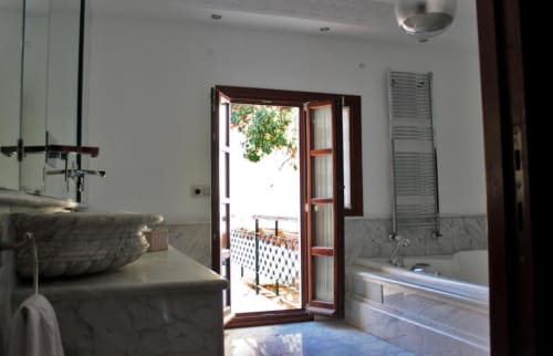 Cuarto de baño de lujo en Suite Comares Granada con acabados en mármol, bañera de inmersión y puertas con vistas a monumentos