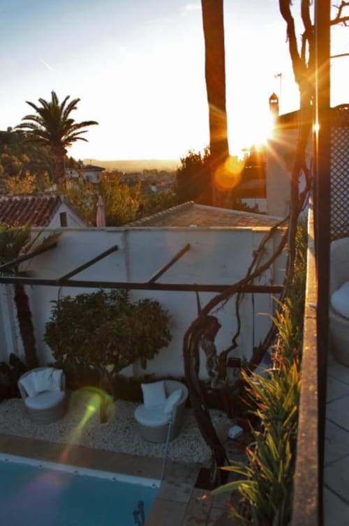 Terraza al atardecer en Suite Comares Granada con muebles blancos, plantas en macetas y vistas al valle