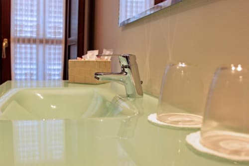Lavabo moderno con grifo cromado y amenidades en el hotel Suite Comares de Granada, España