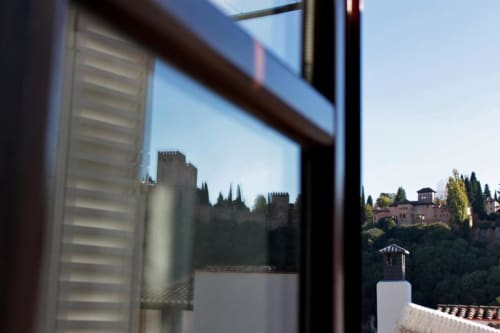 Vista de la habitación Suite Comares Granada con el Palacio de la Alhambra, torres del castillo y cipreses