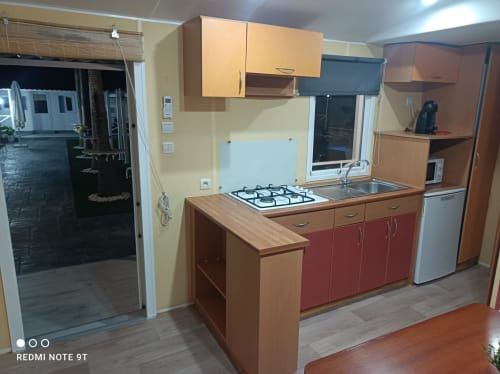 Kitchen area in Bungalow B at Buda Beach hotel, Chipiona with gas cooktop, red cabinetry and garden view