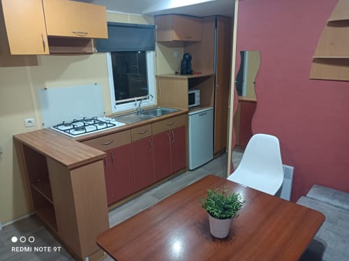 Modern kitchen and dining area in Bungalow B at Buda Beach hotel, Chipiona with red cabinets, gas stove, and garden view