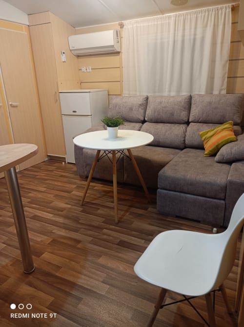 Cozy living room in Bungalow D at Buda Beach, Chipiona with gray sofa, white round table, and modern amenities