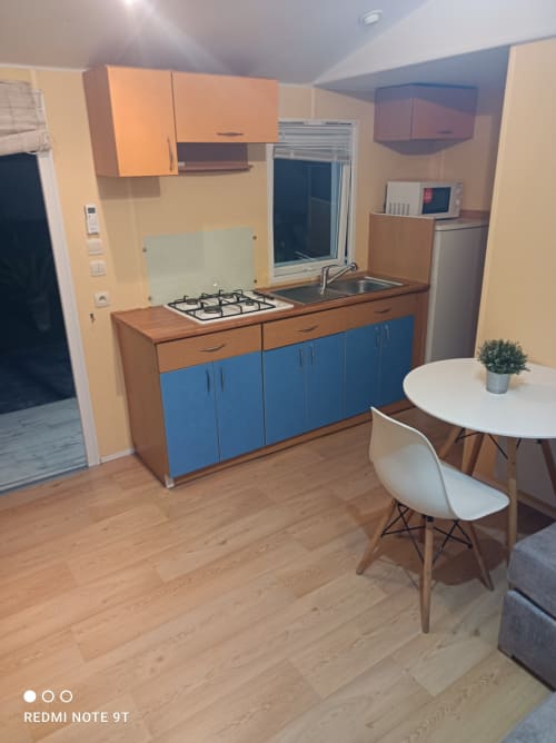 Modern kitchen-dining area in Bungalow E at Buda Beach hotel, Chipiona, featuring blue cabinetry and gas stove