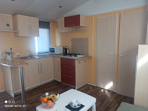 Modern kitchen area in Bungalow G at Buda Beach Chipiona with light wood cabinets, burgundy accents, and dining area