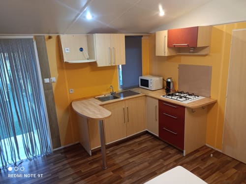 Modern kitchen in Bungalow G at Buda Beach Chipiona with orange walls, wooden cabinets, gas cooktop, and breakfast bar