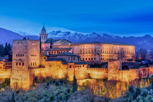 Hotel Suite Comares en Granada con vista al Palacio de la Alhambra iluminado al atardecer y Sierra Nevada nevada
