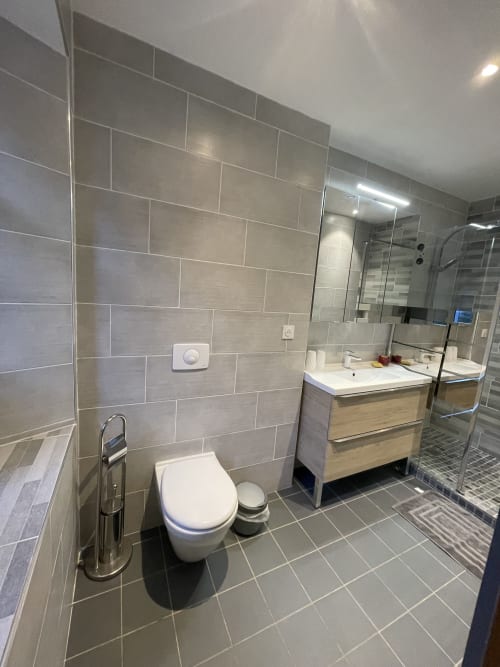 Salle de bains moderne à La Montagnette B&B à Moutiers avec murs carrelés, toilettes, meuble vasque en bois et douche avec paroi vitrée