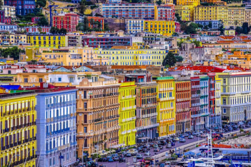 Edifici colorati a Napoli con vivaci facciate gialle, rosse e blu che si affacciano su una piazza sul mare