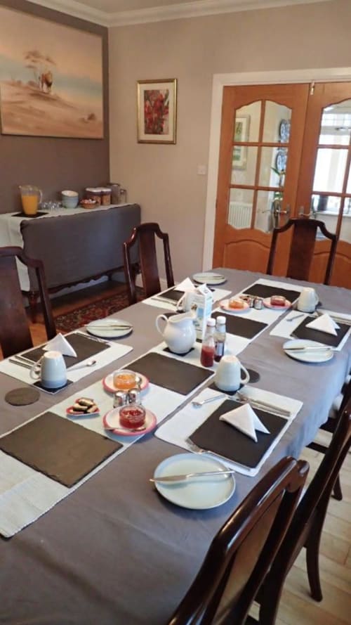 Elegantly set dining table at Arrochoile B&B Glasgow with white linens, place settings, and breakfast items