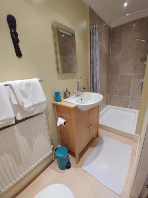 Modern bathroom in Arrochoile Glasgow hotel with wooden vanity, white sink, shower cubicle, and heated towel rail