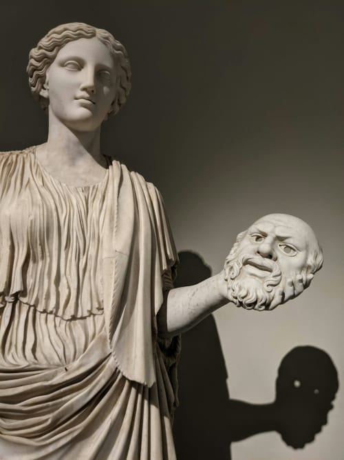 Sculture classiche in marmo all'Hotel Encanto Naples, con figura drappeggiata che regge un busto filosofico