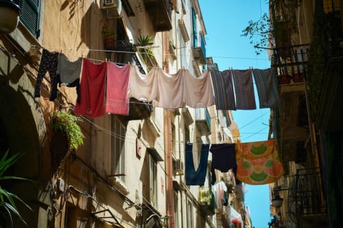 Bucato colorato appeso tra gli edifici storici del quartiere Encanto a Napoli, che mostra la vita di strada locale