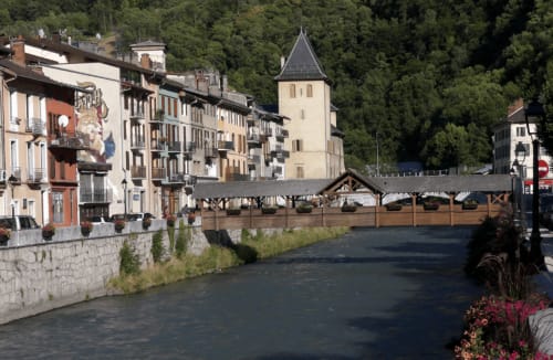 Petite ville médiévale au bord de la rivière avec bâtiments colorés et clocher, Moutiers France