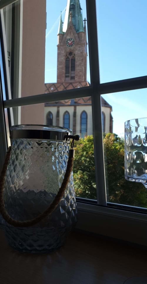 Vase en cristal sur le rebord de fenêtre avec vue sur la tour de l'église gothique de Cernay, Théière & Couverts
