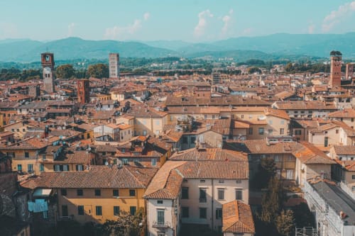 Vista aerea dei tetti in terracotta e delle torri storiche di Lucca con le montagne toscane sullo sfondo
