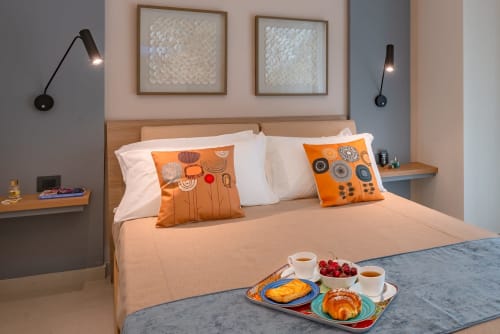 Camera moderna a Macramè Fazello a Sciacca con cuscini arancioni, applique e vassoio colazione sul letto.