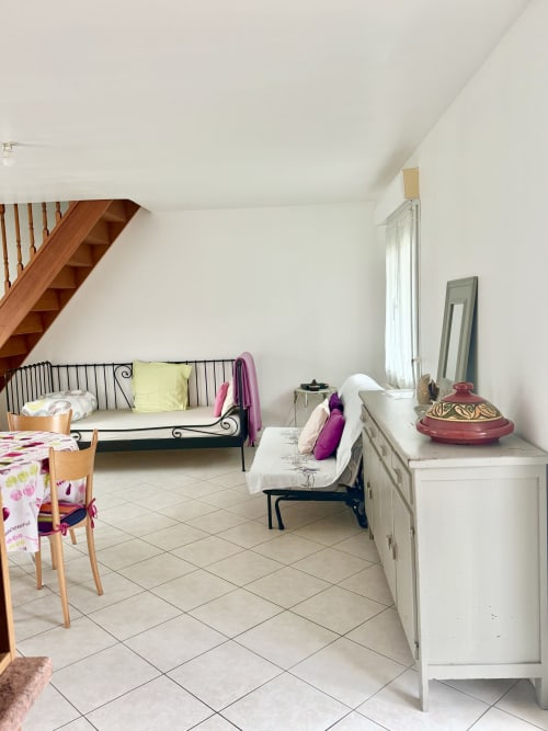 Light cottage bedroom at Le Clos De La Vallée with twin beds, dining area, wooden stairs, and garden view windows
