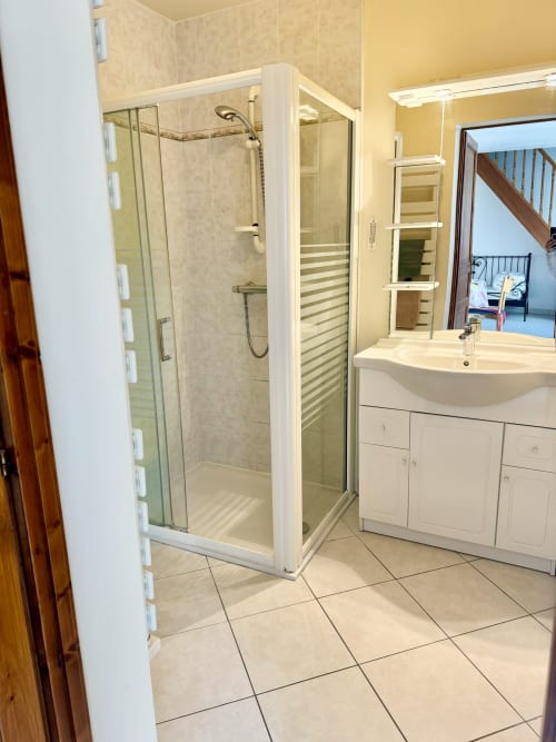 Modern bathroom with glass shower enclosure, white vanity sink, mirrored cabinet, and heated towel rack at Le Clos cottage in