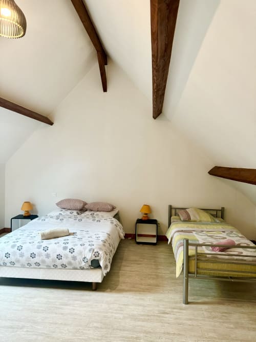 Cozy bedroom at Le Clos De La Vallée cottage with two beds, wooden beams, and garden view in Bellengreville, France