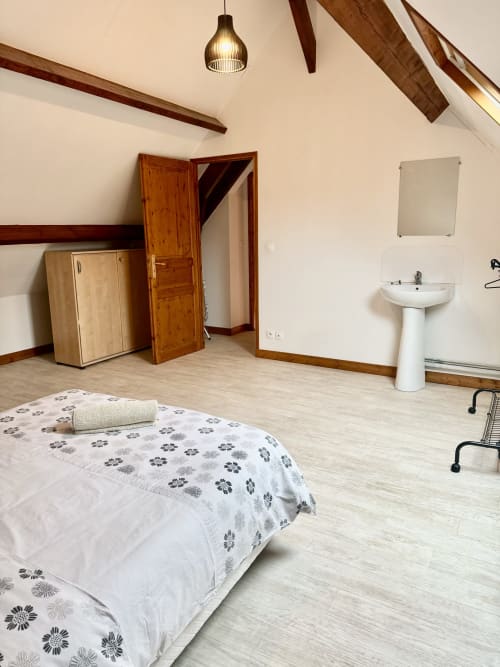 Le Clos 2 cottage bedroom with bed, pedestal sink, wooden beams, and garden view at Le Clos De La Vallée in Bellengreville