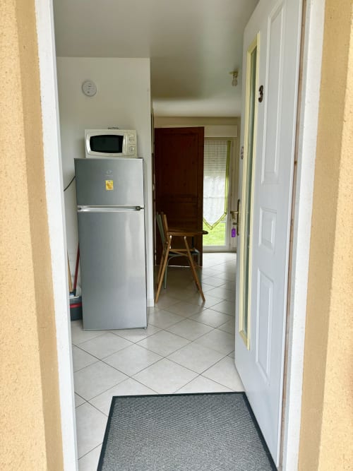 Kitchen entrance at Le Clos cottage with refrigerator, microwave, and dining area visible in Bellengreville, France