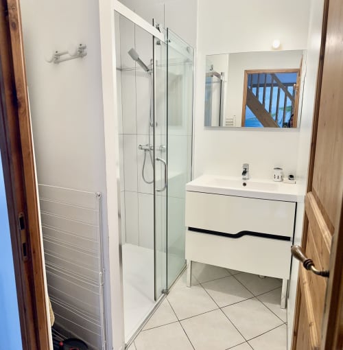 Modern bathroom in Le Clos 3 cottage with glass shower enclosure, white vanity sink, and heated towel rack at Le Clos De La