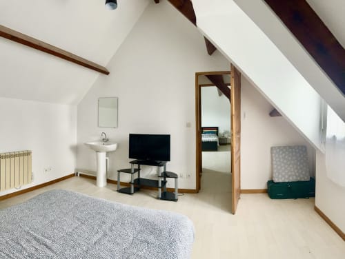 Cozy attic bedroom at Le Clos De La Vallée cottage with TV, sink, wooden beams and garden view