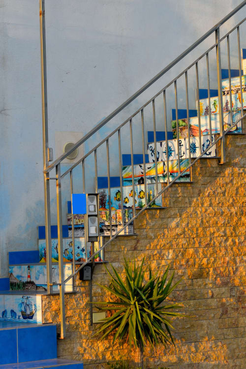 Scalinata piastrellata e colorata presso le camere Macramè Fazello a Sciacca, Sicilia, con decorazioni blu e gialle d'ispirazione mediterranea
