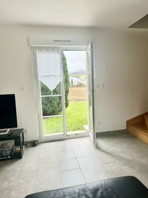 Open French doors leading to garden at Le Clos De La Vallée cottage in Bellengreville, with tiled floor and sitting area view