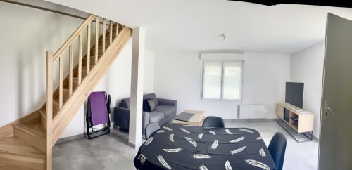 Le Clos 5 cottage living room with mezzanine stairs, dining table, seating area, TV, and garden view in Bellengreville